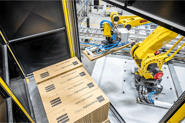 Le bras robotisé soulève le carton avec les panneaux de fond