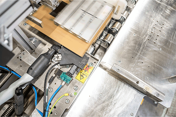 Application latérale de colle en cordon avec la tête d'application SX sur la boîte en carton pliable