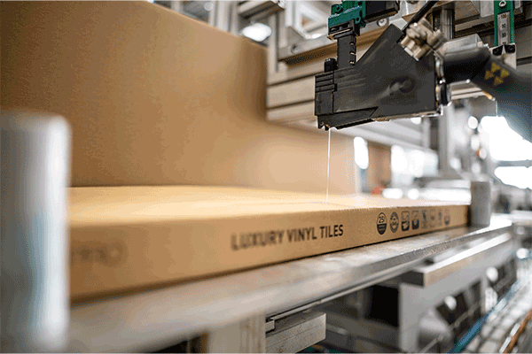 Raupenauftrag mit Auftragskopf SX von oben auf die Faltkartonschachtel