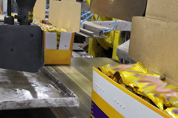 Contenitore di raccolta montato sotto una pistola modello Volta Robatech, utilizzata in un impianto di confezionamento.