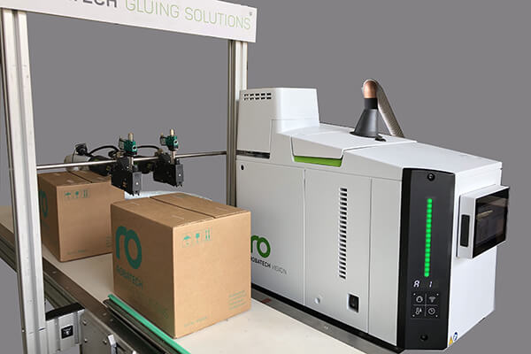 Fondoir Vision, tuyau chauffant Performa et deux têtes d'injection SX appliquant des cordons sur des caisses Robatech (situation de démonstration)