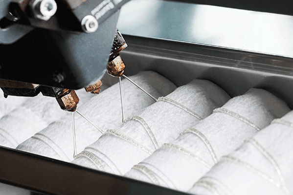 Four beads of hot melt adhesive are applied with two angled nozzles