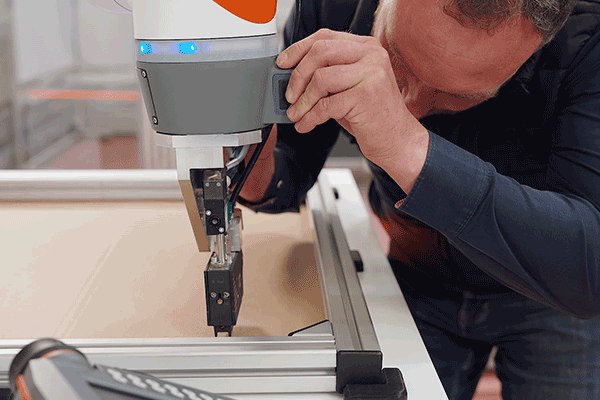 Techniker programmiert das Bewegungsmuster eines Cobots für den Klebstoffauftrag