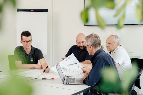 プロジェクト営業チームがテーブルで技術図面について話し合う 